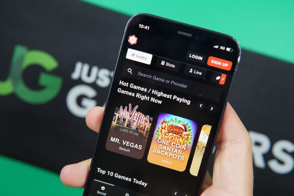Patrik Lidin holding an iPhone with the BetcoinSocial casino library page loaded on the webpage.