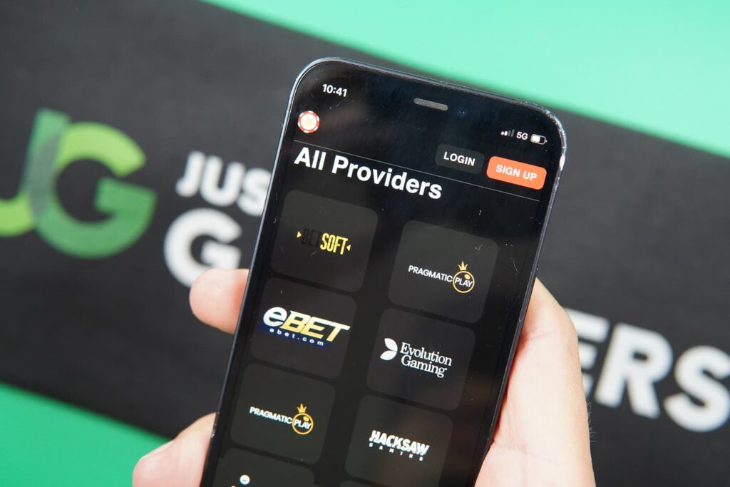 Patrik Lidin holding an iPhone with the BetcoinSocial casino providers page loaded on the webpage.