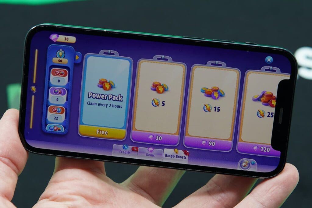 Patrik Lidin holding an iPhone with the Bingo Blitz bingo app purchases page loaded.