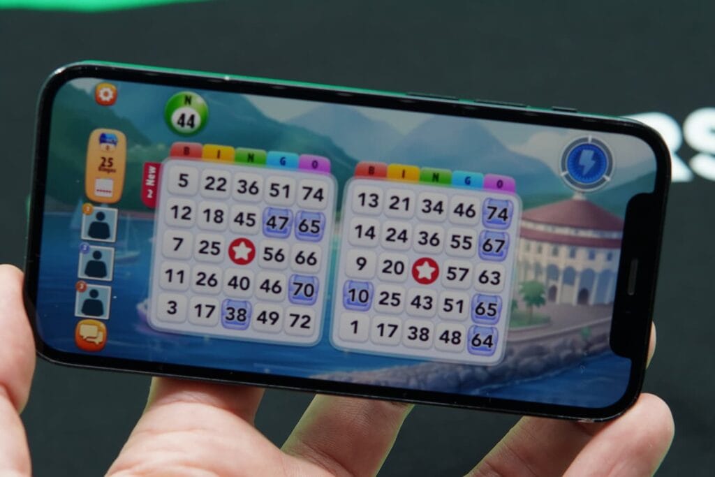 Patrik Lidin holding an iPhone with the Bingo Blitz bingo app game section page loaded.
