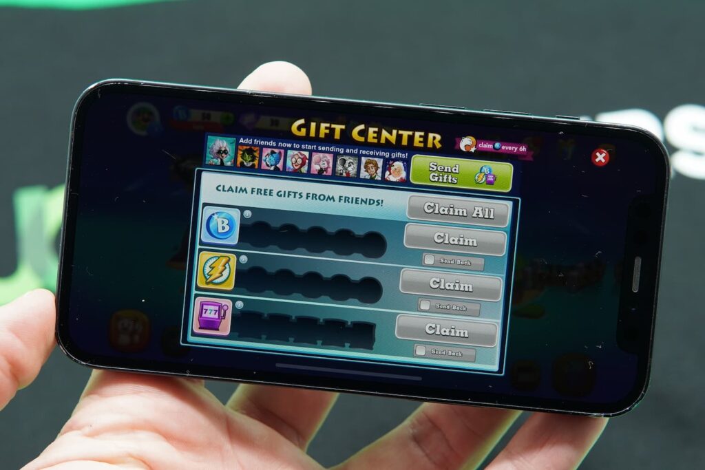 Patrik Lidin holding an iPhone with the Bingo Blitz bingo app promotions page loaded.