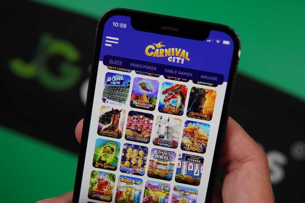 Patrik Lidin holding an iPhone with the Carnival Citi casino game library page loaded on the webpage.