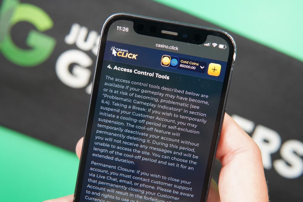 Patrik Lidin holding an iPhone with the Casino Click casino responsible gaming page loaded on the webpage.