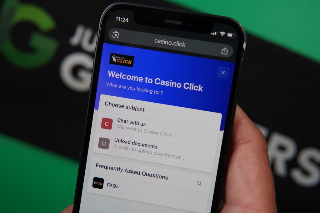 Patrik Lidin holding an iPhone with the Casino Click casino support page loaded on the webpage.