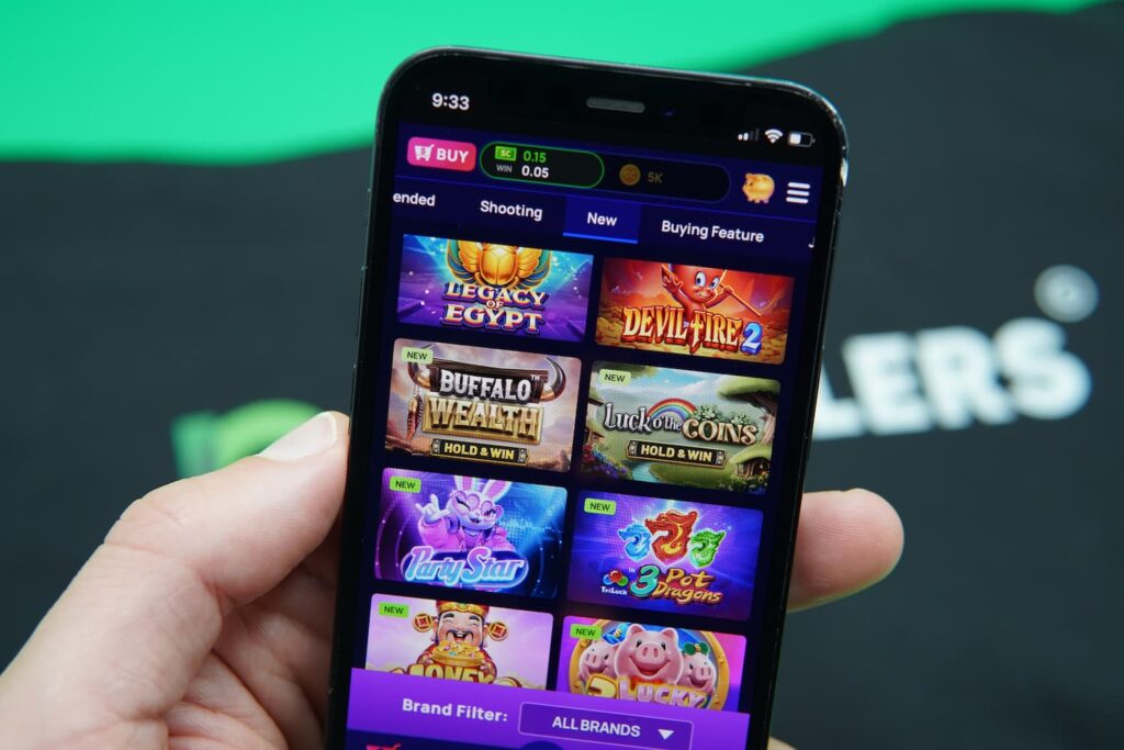 Patrik Lidin holding an iPhone with the Coolspin casino game library page loaded on the webpage.