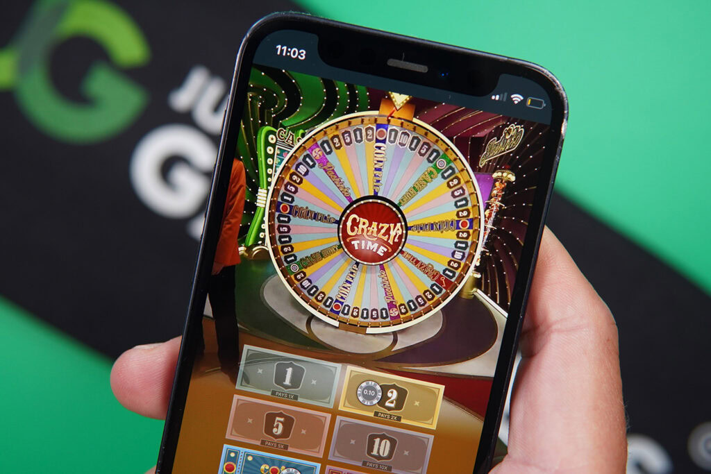 Photo of Patrik Lidin holding an iPhone showing live dealer game Crazy Time.