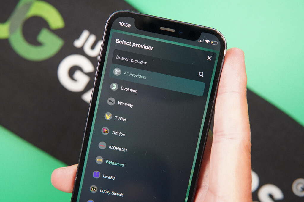 Photo of Patrik Lidin holding an iPhone showing a long list of live dealer software providers.