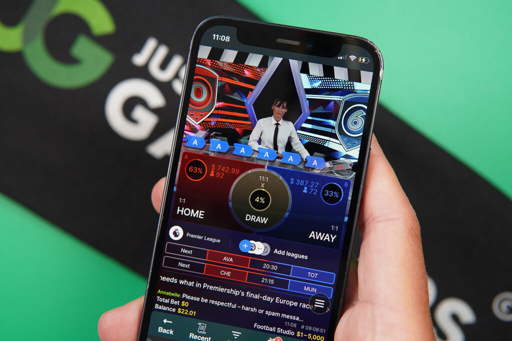 Photo of Patrik Lidin holding an iPhone showing live dealer game Football Studio Live.