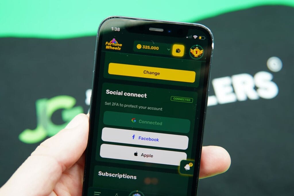 Patrik Lidin holding an iPhone with the Fortune Wheelz casino 2FA page loaded on the webpage.