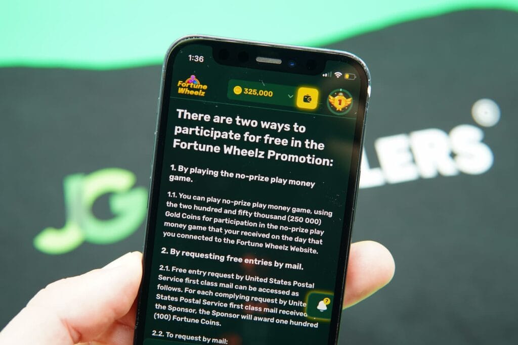 Patrik Lidin holding an iPhone with the Fortune Wheelz casino AMOE page loaded on the webpage.