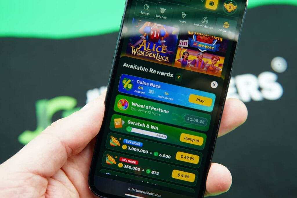 Patrik Lidin holding an iPhone with the Fortune Wheelz casino promotions page loaded on the webpage.