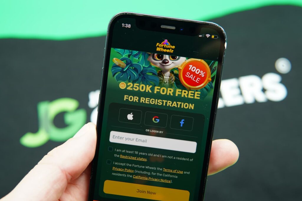 Patrik Lidin holding an iPhone with the Fortune Wheelz casino registration page loaded on the webpage.