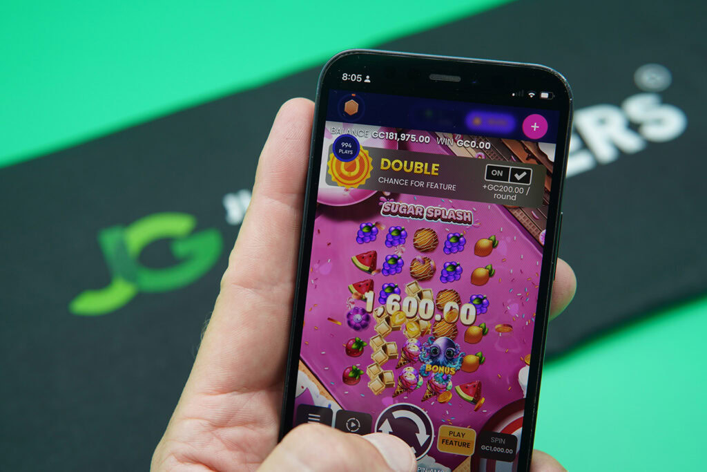 Patrik Lidin holding an iPhone with Funrize casino game Sugar Splash showing.