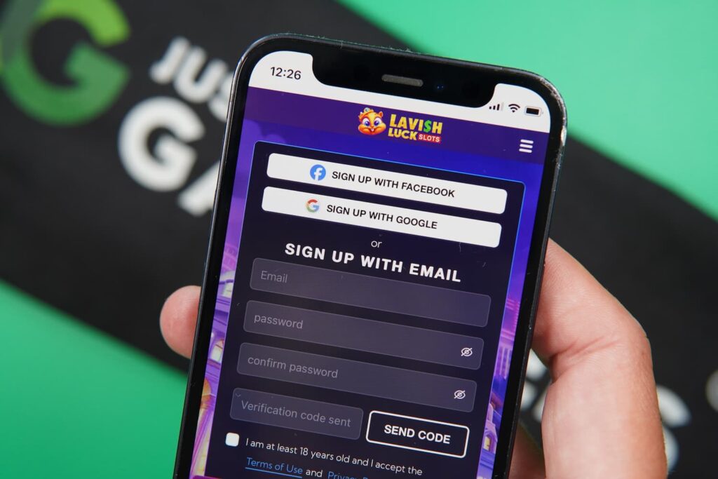 Patrik Lidin holding an iPhone with the Lavish Luck casino registration page loaded on the webpage.