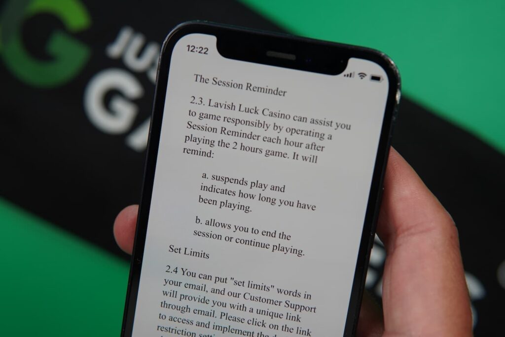 Patrik Lidin holding an iPhone with the Lavish Luck casino Responsible Gaming page loaded on the webpage.