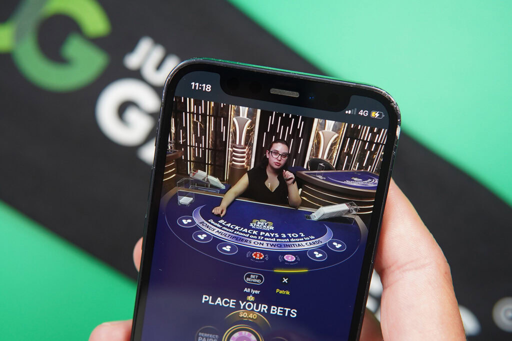 Photo of Patrik Lidin holding an iPhone showing live dealer game BlackJack.