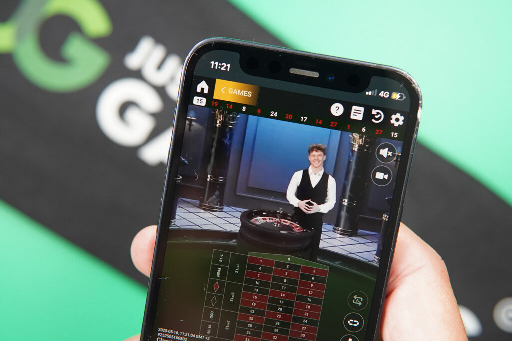 Photo of Patrik Lidin holding an iPhone showing live dealer game American Roulette.