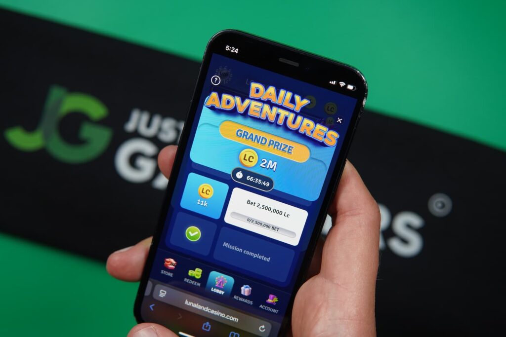 Patrik Lidin holding an iPhone with the Lunaland casino daily mission page loaded on the webpage.