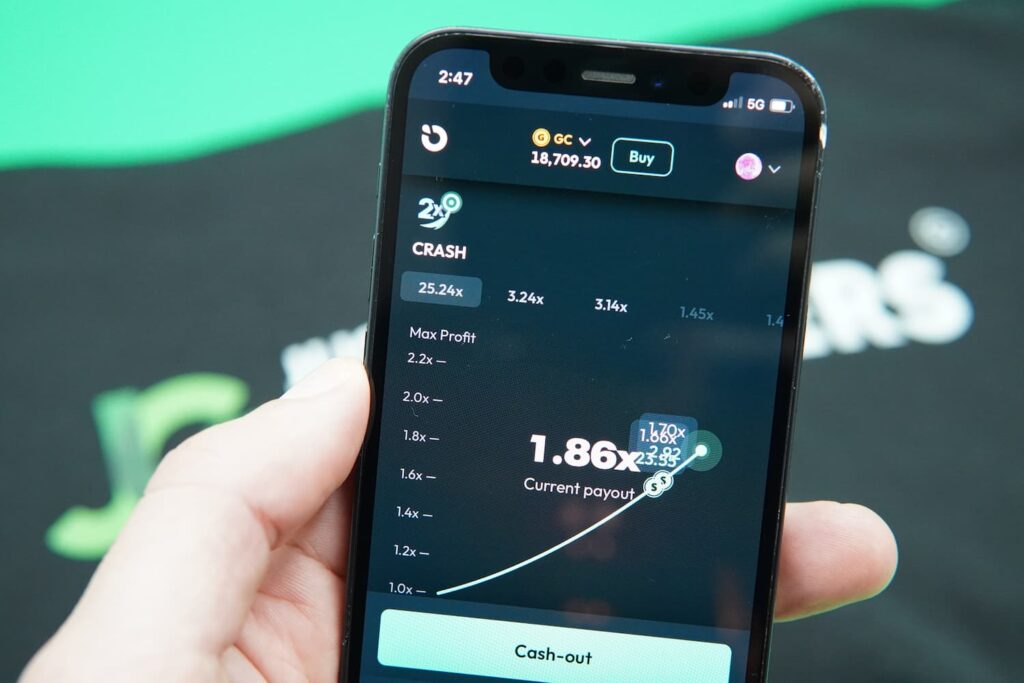 Patrik Lidin holding an iPhone with the Moonspin in-game mobile page loaded on the webpage.