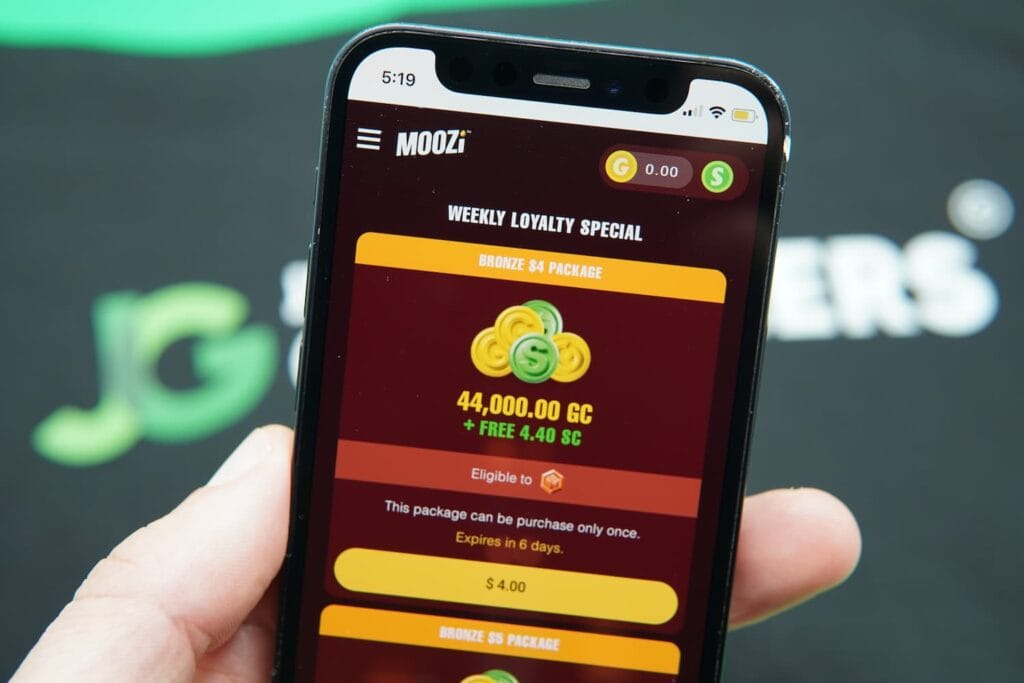 Patrik Lidin holding an iPhone with the Moozi casino coin purchase page loaded on the webpage.