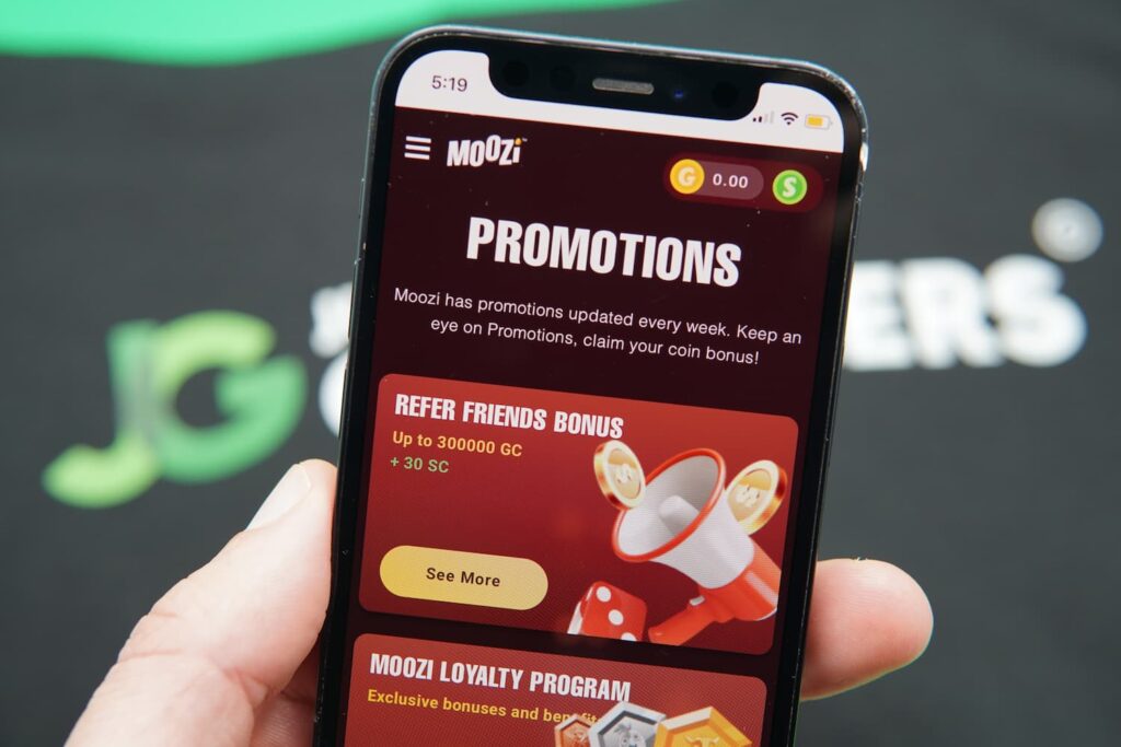 Patrik Lidin holding an iPhone with the Moozi casino promotions page loaded on the webpage.