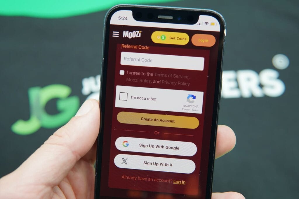 Patrik Lidin holding an iPhone with the Moozi casino registration page loaded on the webpage.