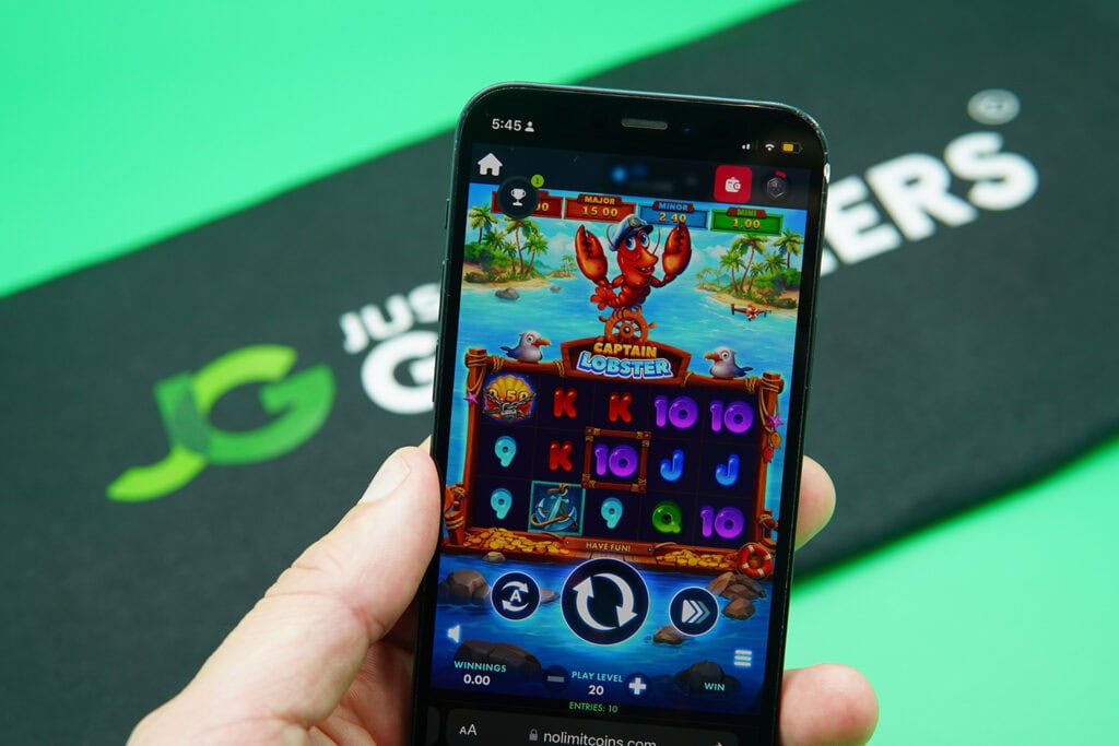 Patrik Lidin holding an iPhone with NoLimitcoins casino game Captain Lobster showing.