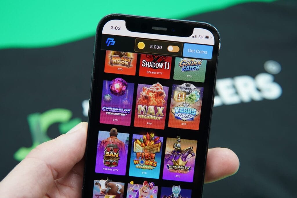 Patrik Lidin holding an iPhone with the PeakPlay casino game library loaded on the webpage.