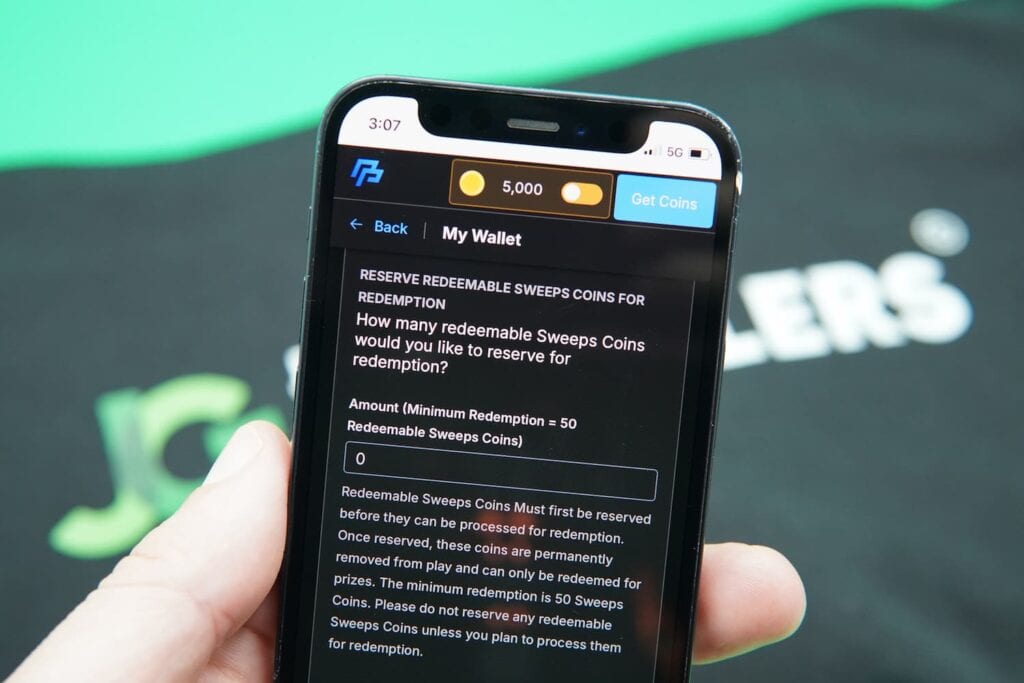 Patrik Lidin holding an iPhone with the PeakPlay casino redemptions page loaded on the webpage.