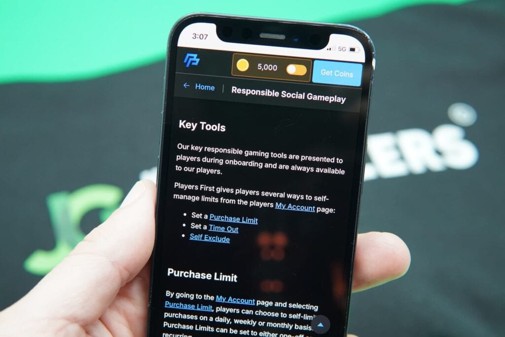 Patrik Lidin holding an iPhone with the PeakPlay casino responsible gambling page loaded on the webpage.