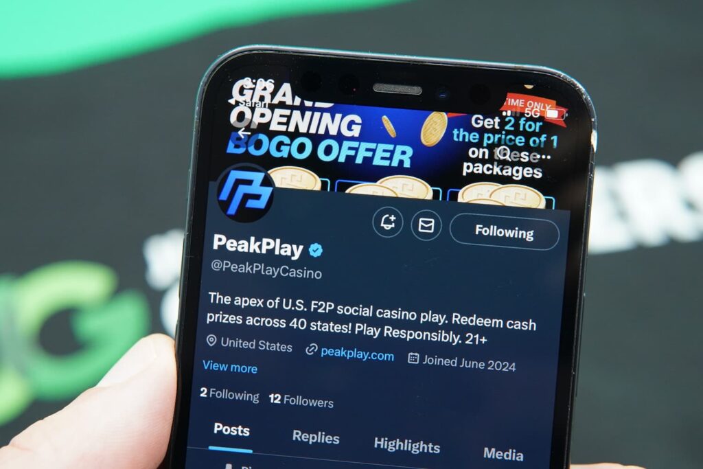 Patrik Lidin holding an iPhone with the PeakPlay casino social media page loaded on the webpage.