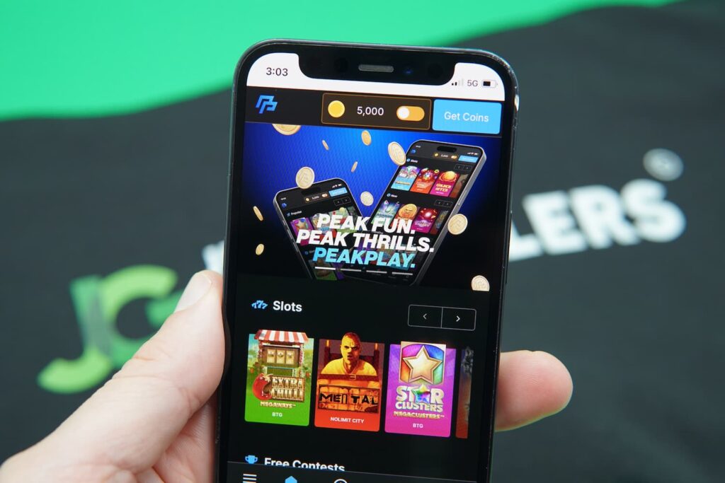Patrik Lidin holding an iPhone with the PeakPlay casino landing page loaded on the webpage.