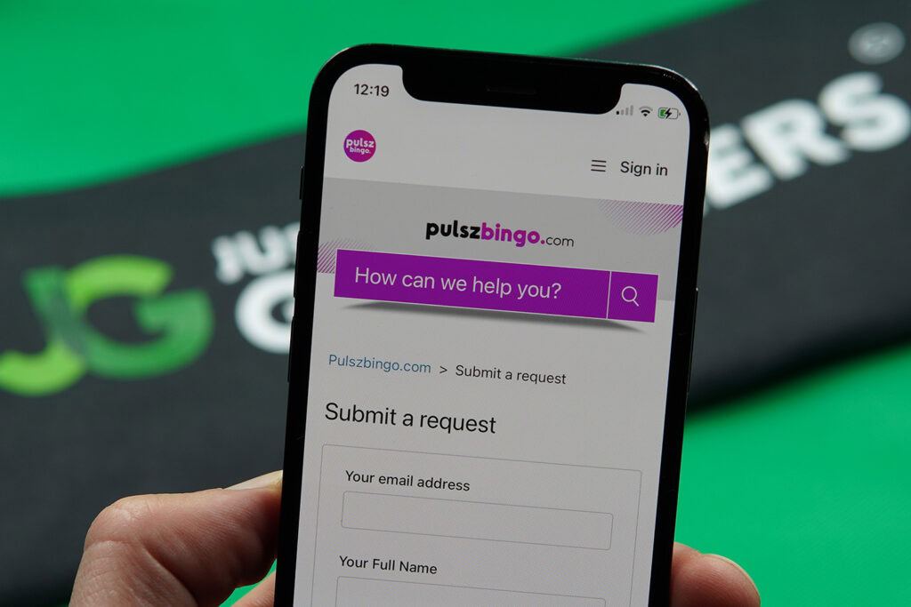 Patrik Lidin holding an iPhone while using the Pulsz Bingo customer support.