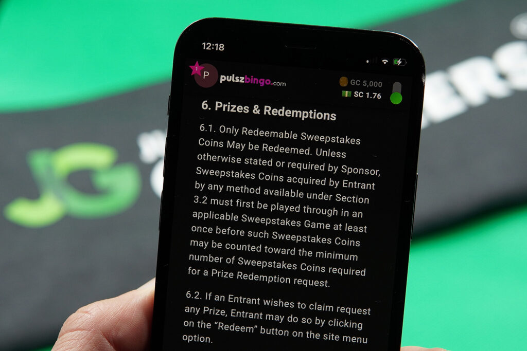 Patrik Lidin holding an iPhone with the Pulsz Bingo redemptions loaded on the webpage.