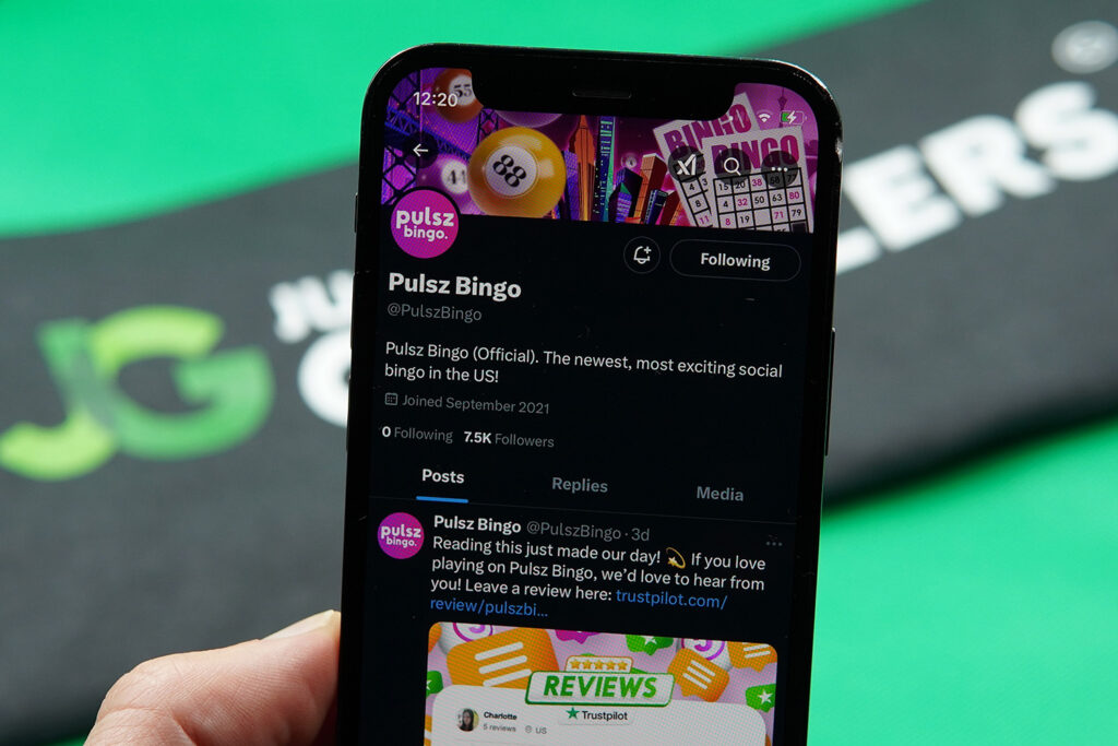 Patrik Lidin holding an iPhone with the Pulsz Bingo X account.