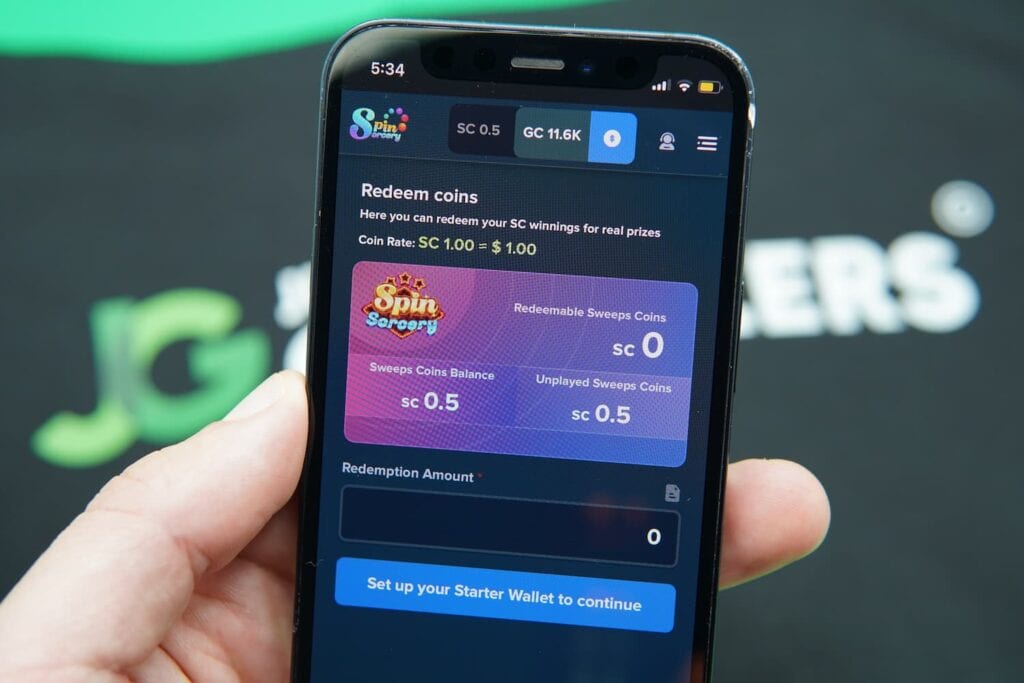 Patrik Lidin holding an iPhone with the Spin Sorcery casino redemptions page loaded on the webpage.