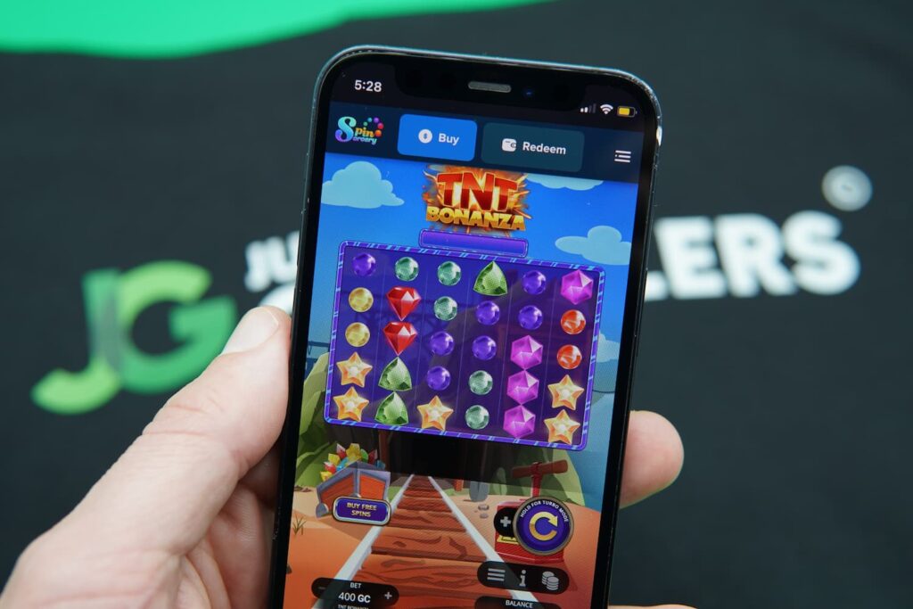 Patrik Lidin holding an iPhone with the Spin Sorcery casino mobile game loaded on the webpage.