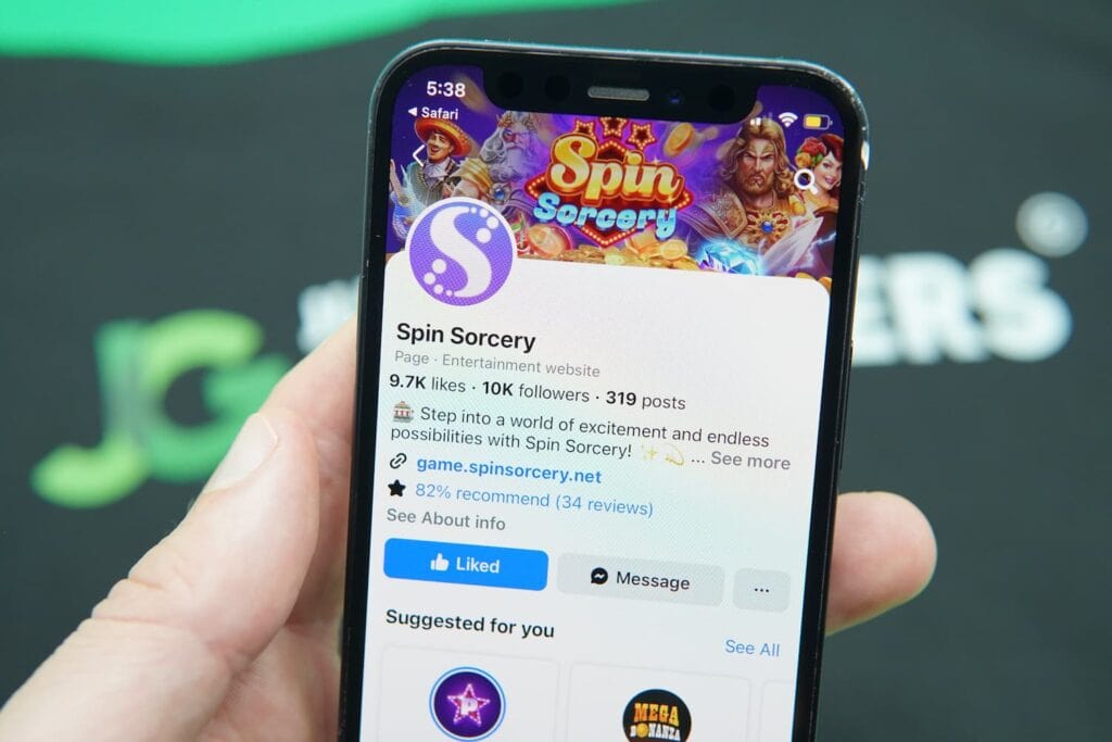 Patrik Lidin holding an iPhone with the Spin Sorcery casino social media Facebook page loaded on the webpage.
