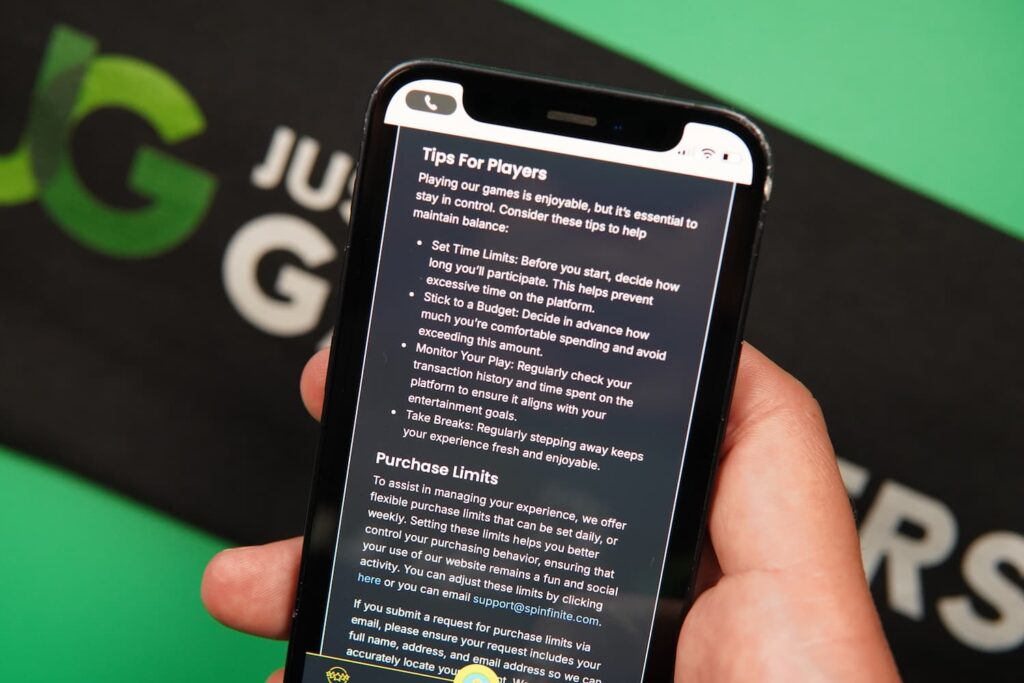 Patrik Lidin holding an iPhone with the Spinfinite casino Responsible Gaming page loaded on the webpage.
