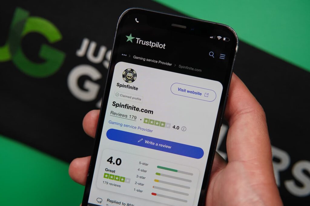 Patrik Lidin holding an iPhone with the Spinfinite casino Trustpilot page loaded on the webpage.