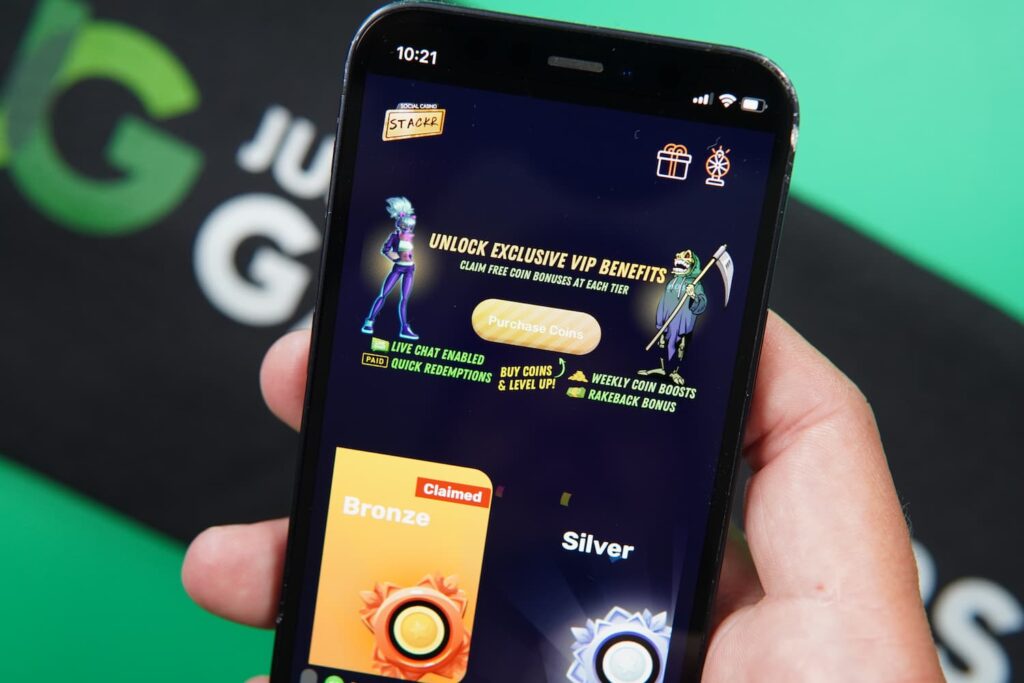 Patrik Lidin holding an iPhone with the Stackr casino VIP page loaded on the webpage.