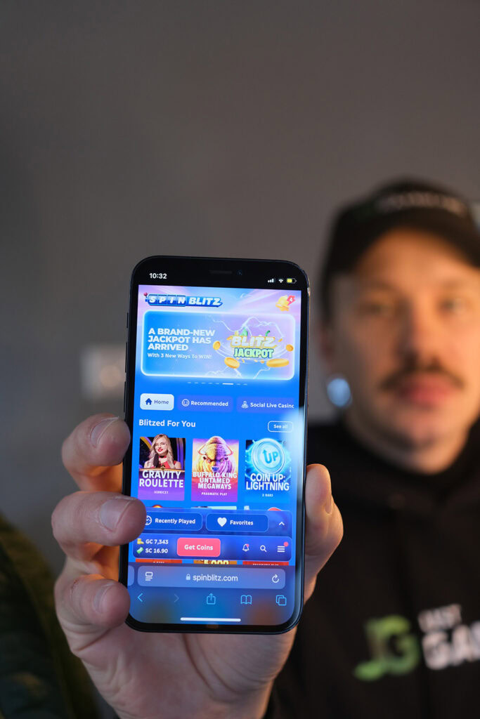 Photo of Patrik Lidin holding his iPhone with the SpinBlitz sweepstakes casino loaded on the screen.