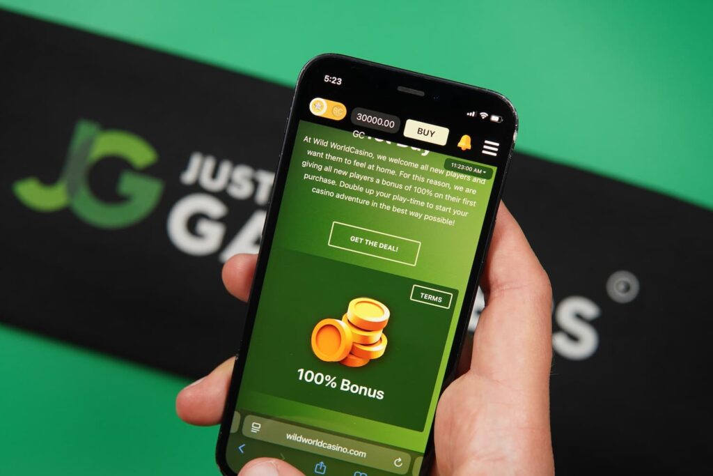 Patrik Lidin holding an iPhone with the Wild World Casino promotions page loaded on the webpage.